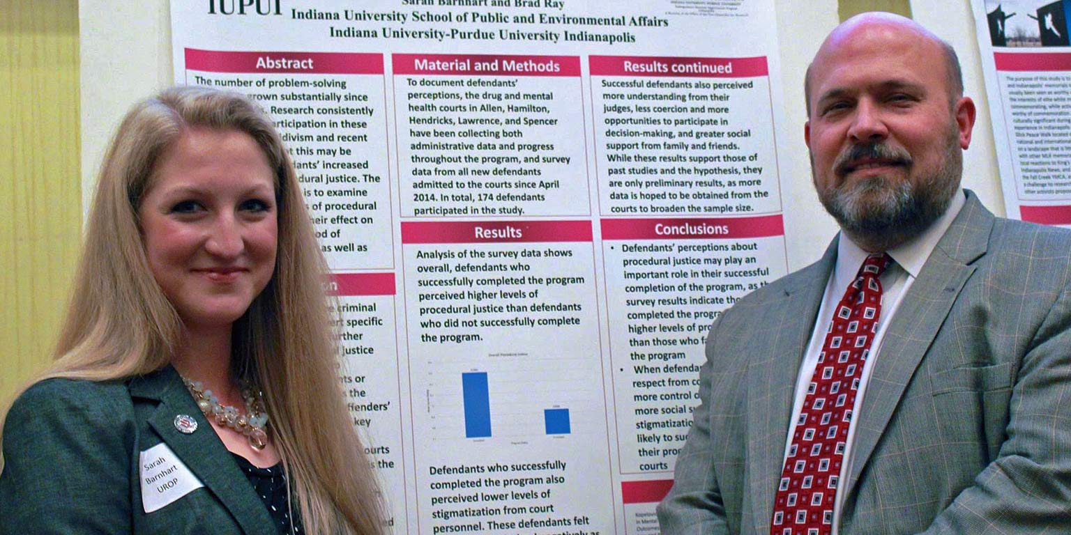  Two researchers present data on a research poster.