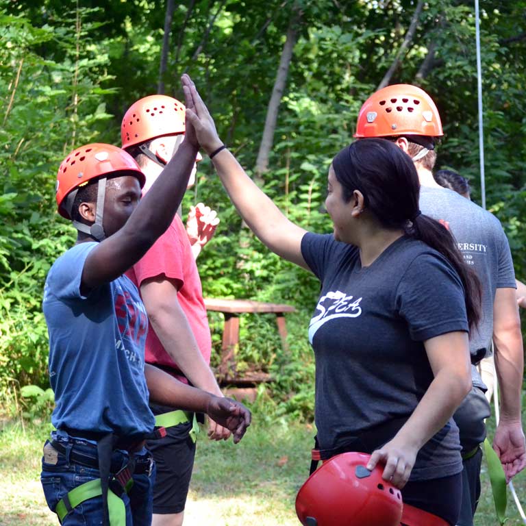 Students complete a ropes course and give each other high fives. 