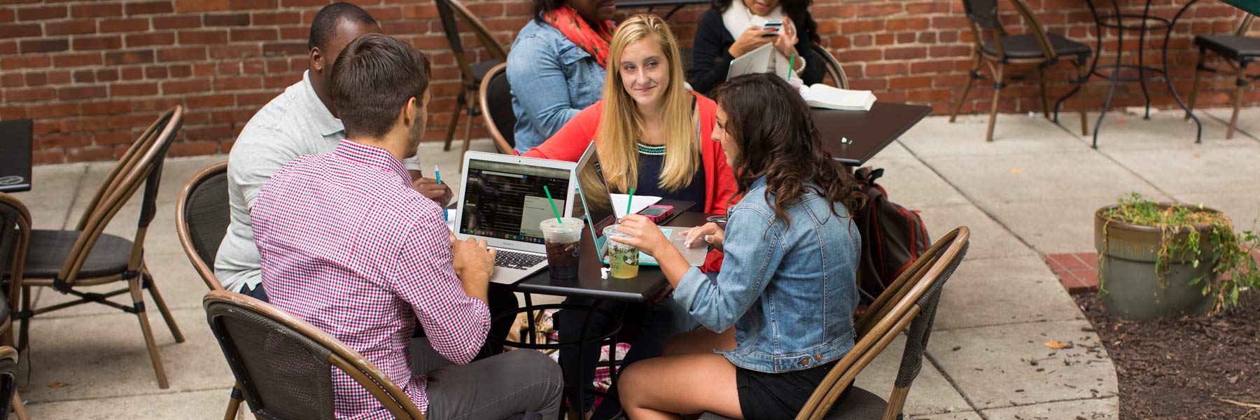 A group of students discuss college in an outdoor courtyard.