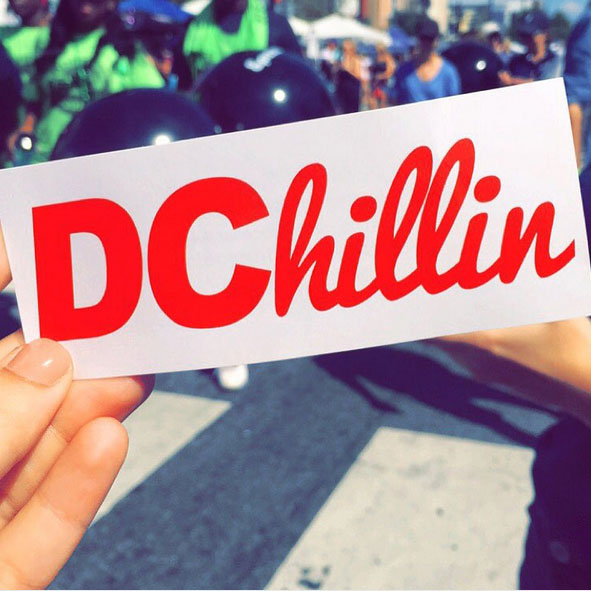 A student holds a bumper sticker that says 'DChillin'.